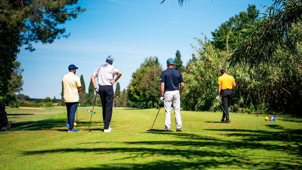 Vediamo quattro uomini giocano a golf in una giornata di sole