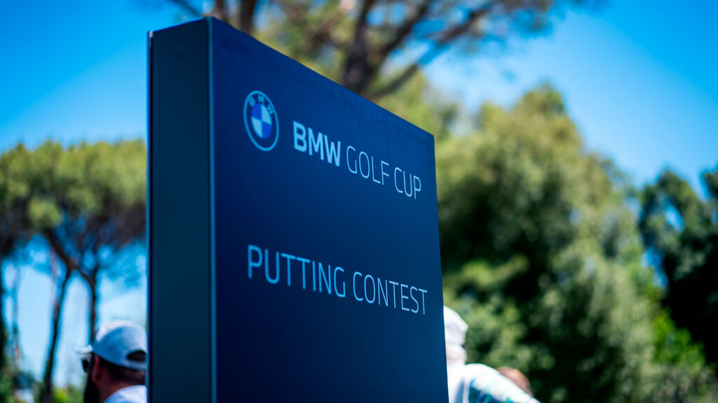 Vediamo un cartello nero e blu con la scritta "BMW Golf Cup - Putting Contest"