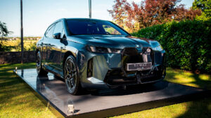 Vediamo una BMW iX, scura esposta su una piattaforma all'aperto