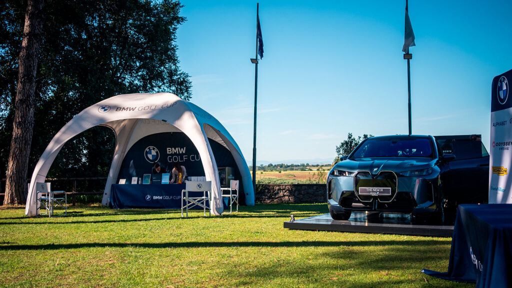 Vediamo un grande stand all'aperto per la BMW Golf Cup con un'auto BMW in esposizione
