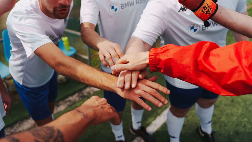 Vediamo alcuni giocatori di calcio che uniscono le mani in segno di squadra e motivazione