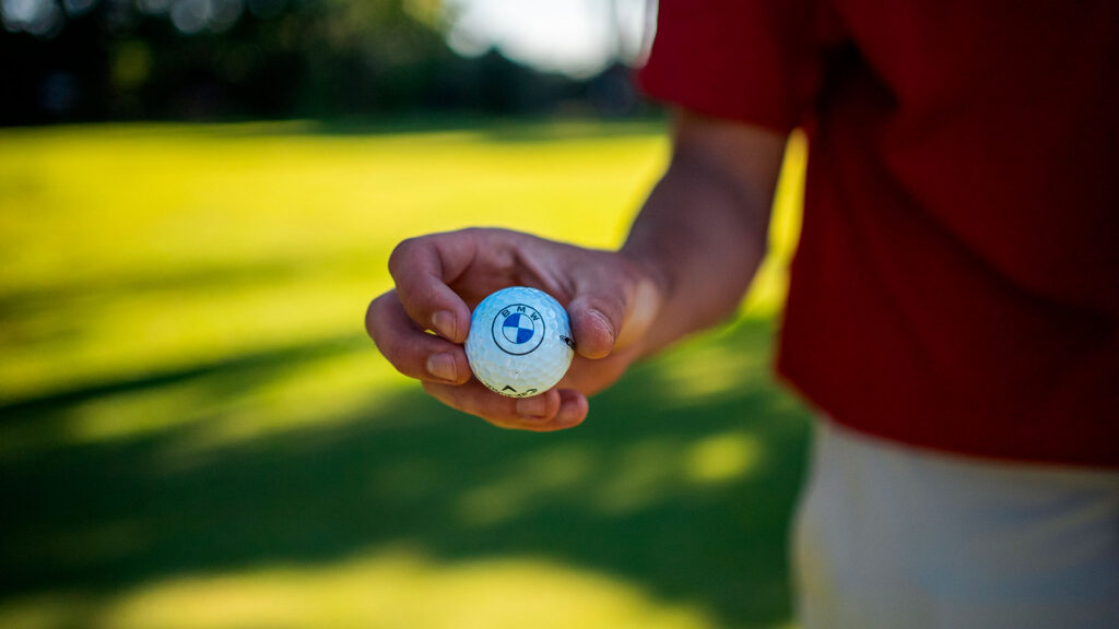 Una persona tiene un'elegante palla da golf con il logo BMW