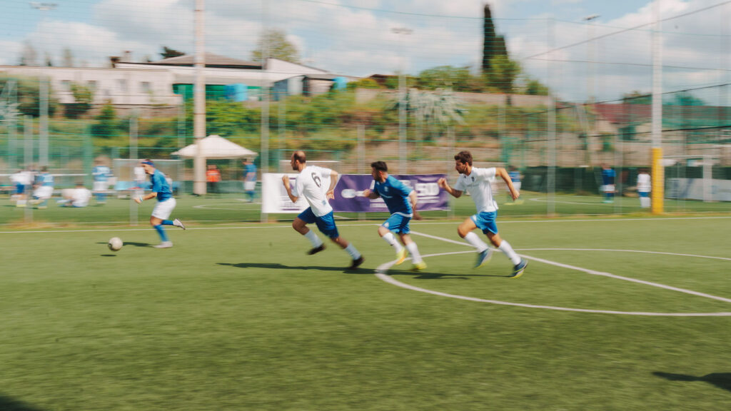 Vediamo dei calciatori che corrono verso il pallone in una partita di calcio