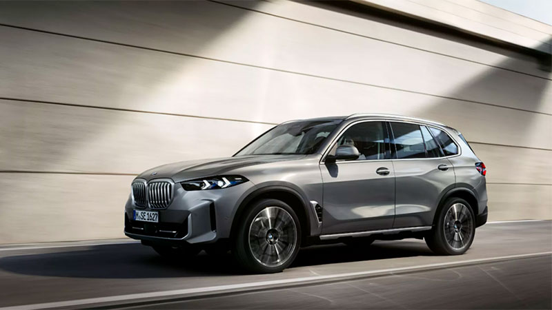 Vediamo una BMW X5 grigia in movimento su una strada