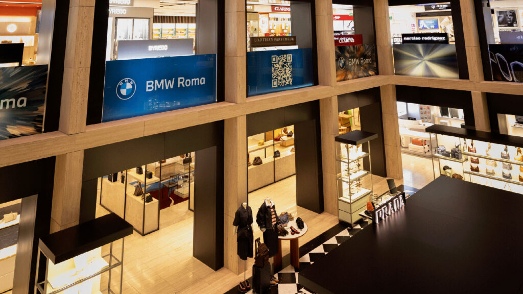 Interno di un grande magazzino di lusso con stand, manichini e cartelli pubblicitari BMW Roma.