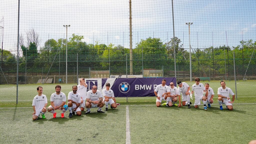 Vediamo una squadra di calcio che posa per una foto davanti a uno striscione BMW.