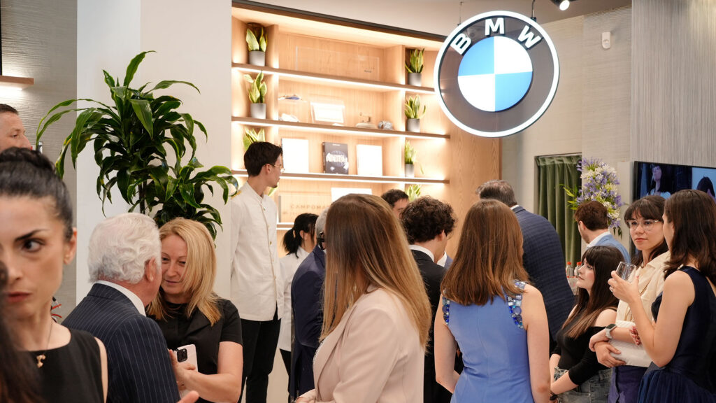 Vediamo un gruppo di persone che chiacchierano all'interno di uno showrrom di BMW Roma