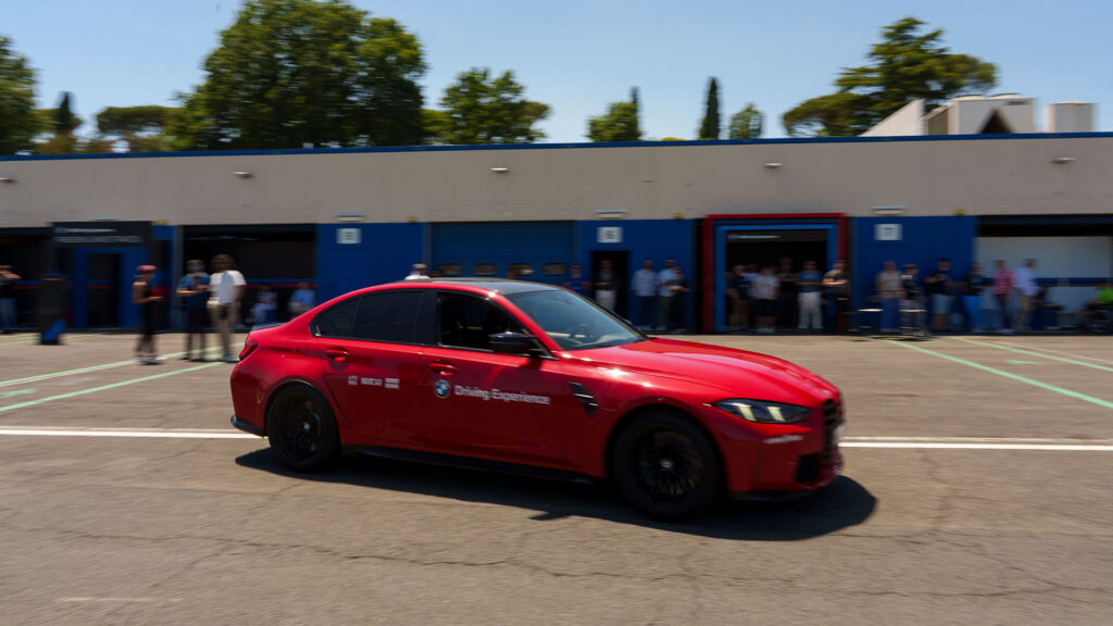 Vediamo una BMW rossa in movimento in un circuito automobilistico