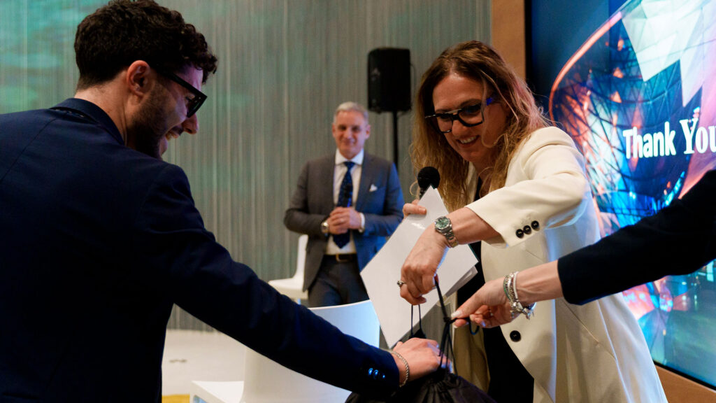 Una donna consegna un premio a un giovane durante un evento di premiazione.