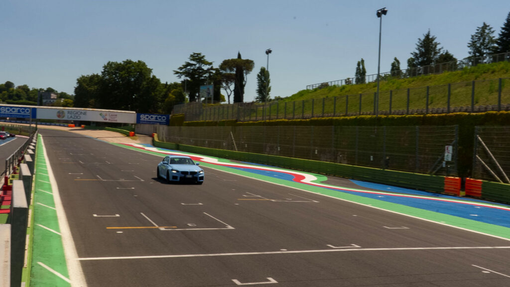 Vediamo una BMW azzurra che corre sul rettilineo del circuito
